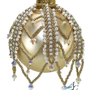 May include: A gold Christmas bauble with a white and gold beaded design. The bauble has a crystal-like drop design.