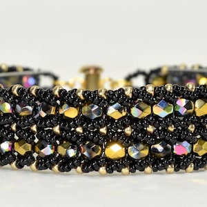 May include: A black and gold beaded bracelet with iridescent accents. The bracelet is made with small beads and has a woven pattern.