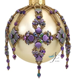 May include: A beaded Christmas ornament with a gold base and purple and green accents. The ornament features a cross-shaped design with dangling beads.