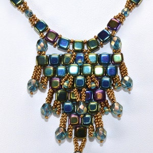 May include: A gold and iridescent blue beaded necklace with a teardrop-shaped pendant. The pendant is made of square beads arranged in a geometric pattern.