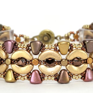 Op de afbeelding: Een gouden, bruine en roze kralen armband met een magneetsluiting. De armband heeft een herhalend patroon van halvemaanvormige kralen en kleinere driehoekige kralen.