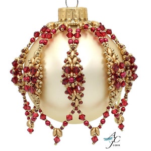 May include: A gold Christmas bauble with a red beaded design. The bauble has a beaded crown and a beaded fringe.