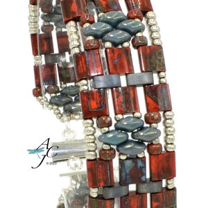 Può includere: Un braccialetto multifilo con perline rosse, grigie e argentate. Il braccialetto è realizzato con una varietà di forme e dimensioni di perline diverse. Il braccialetto è progettato in un motivo geometrico.