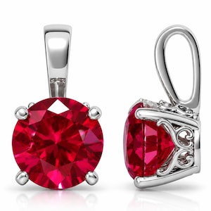 May include: A silver pendant featuring a round, faceted, vibrant red gemstone held by four prongs. The setting includes a decorative, openwork metal gallery and a polished silver bail at the top for attachment to a chain or necklace.