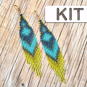 Könnte beinhalten: Ein Paar Perlenohrringe mit Federdesign. Die Ohrringe haben einen Farbverlauf aus gelben, türkisfarbenen und marineblauen Perlen. Die Ohrringe haben goldfarbene Ohrhaken. Das Wort "KIT" befindet sich in einem weißen Rechteck.
