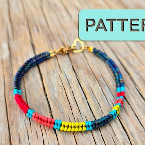 Puede incluir: Una colorida pulsera de cuentas con un cierre dorado en forma de corazón. La pulsera presenta secciones de cuentas rojas, amarillas y azules, con la palabra "PATTERN" en un cuadro azul claro en el fondo.
