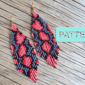 May include: A pair of long, beaded earrings with a geometric pattern in shades of pink, black, and purple. The earrings are hanging from gold hooks.