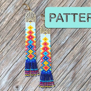 Op de afbeelding: Een paar lange, geperde oorbellen met een geometrisch patroon in rood, geel, blauw en wit. De oorbellen hebben een gouden zonnestralenontwerp aan de bovenkant en hangen aan gouden haken.