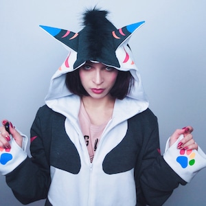 May include: A white and black hooded sweatshirt with colorful paw prints on the cuffs. The hood has a black and white animal head design with colorful accents.