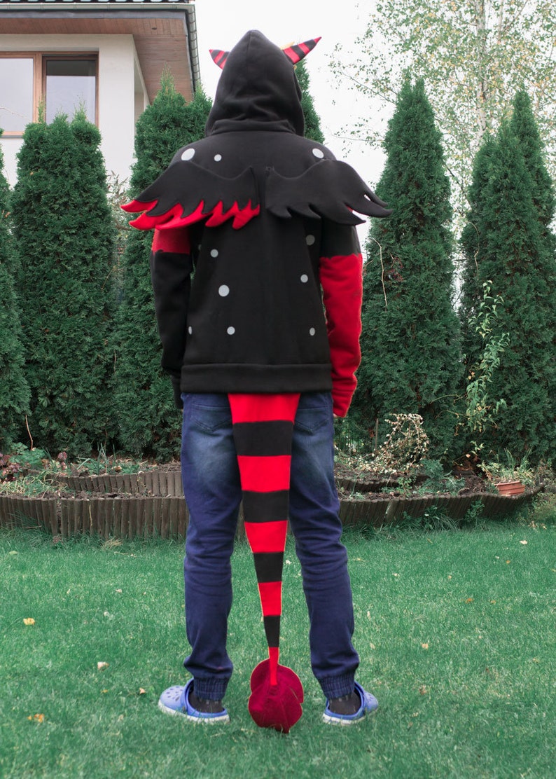 May include: A black hoodie with red and black wings and a long red and black tail. The hoodie has white polka dots and a zipper.