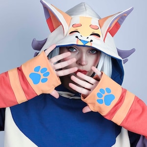 May include: A person wearing a white, orange, and blue hooded sweatshirt with a cartoon fox face on the hood. The sweatshirt has paw prints on the sleeves.
