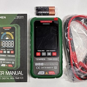 May include: A green and black digital multimeter with a user manual, batteries, and test leads. The multimeter has a digital display showing numbers and symbols. The user manual reads "USER MANUAL SMART DIGITAL MULTIMETER".