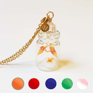 My happy family in origami cranes. Parents and kids on a nest. Gold-plated necklace with a glass bottle
