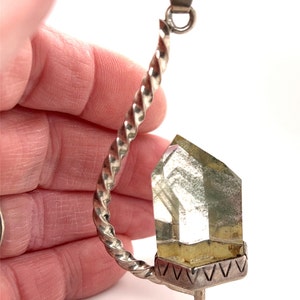 May include: A silver pendant with a twisted chain and a clear quartz crystal point. The crystal is set in a silver base with a decorative design.