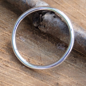 Peut inclure: Une simple bague en argent, posée sur une surface en bois.