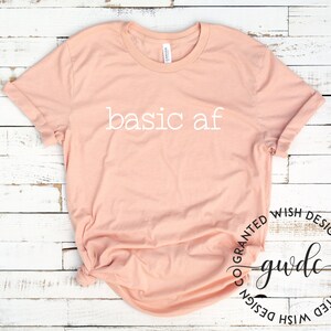 May include: A peach-colored t-shirt with the text "basic af" printed in white on the front.
