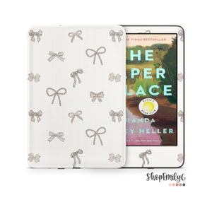 May include: A white Kindle e-reader with a cover featuring a pattern of beige bows. The cover is shown open to reveal the book "The Paper Palace" by Miranda Cowley Heller.