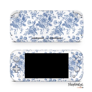 Peut inclure: Console Nintendo Switch Lite blanche avec une peau à motif floral bleu et blanc. La peau présente un motif répétitif de fleurs bleues et de feuilles sur un fond blanc.