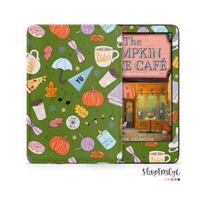 Può includere: Una custodia verde per Kindle Paperwhite con un motivo autunnale con zucche, foglie, tazze da caffè e il testo "The Pumpkin Cafe".