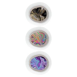 May include: Three round, white patches with different abstract designs. The top patch has a black and gold swirl design. The middle patch has a colorful swirl design. The bottom patch has a purple and blue swirl design.