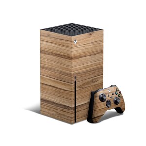 May include: An Xbox Series X console and matching controller with a wood-grain pattern. The console is a rectangular box with a black top and a wood-grain pattern on the front and sides. The controller is black with a wood-grain pattern on the back.