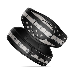 May include: Two black MagicBand wristbands with a distressed American flag design. The flag is in black and white with a faded look.