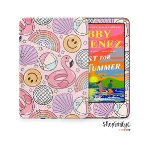 May include: An e-reader device featuring a protective cover with a light pink background patterned with pink flamingos, yellow smiley faces, purple seashells, beach balls, disco balls, rainbows, and small stars, displaying a book cover on screen.