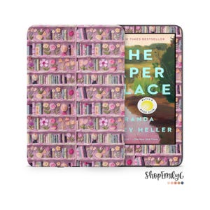 May include: A pink and white patterned Kindle cover with a book cover on the screen. The book cover is for "The Paper Place" by Miranda Gray Heller. The book cover is blue and green with a lake scene.