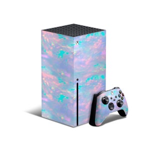 Könnte beinhalten: Eine weiße und schillernde Xbox Series X Konsole mit passendem Controller. Die Konsole hat ein wirbelndes Muster in Rosa, Blau und Grün.