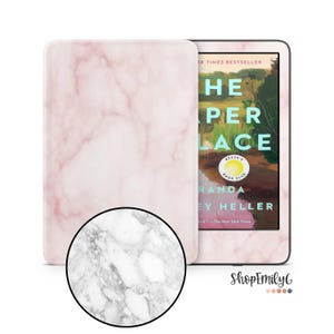 Op de afbeelding: Een roze marmerpatroon e-reader hoesje naast een e-reader met de boekomslag van "The Paper Palace" van Miranda Cowley Heller. De omslag heeft de tekst "The Paper Place" en "Reese's Book Club".