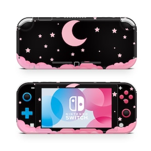 Puede incluir: Una consola Nintendo Switch Lite negra con un diseño rosa y negro que presenta una luna creciente y estrellas. La consola tiene una disposición de botones rosa y negra.