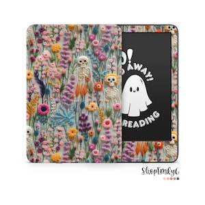 May include: A black and white illustration of a ghost with the text "Boo! Go Away! Reading" on a black background. The background of the Kindle case is a colorful floral embroidery pattern with skeletons.