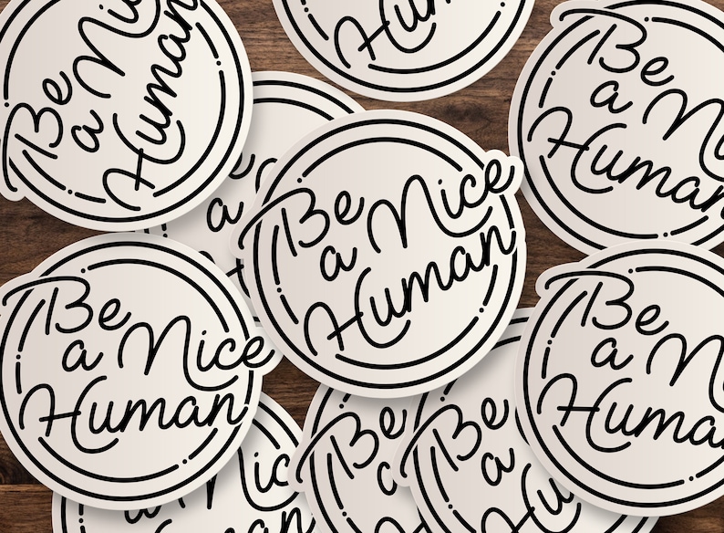 Puede incluir: Primer plano de varias pegatinas redondas con el texto "Be a Nice Human" escrito en letras cursivas negras sobre fondo blanco.