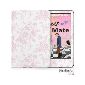 Puede incluir: Un lector electrónico con una funda protectora que presenta un patrón floral rosa claro sobre un fondo blanco. La pantalla muestra la portada del libro Check & Mate de Ali Hazelwood, con una ilustración de dos personas tomadas de la mano en un tablero de ajedrez.