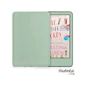 May include: A green e-reader with a cover on it. The e-reader is displaying the cover of a book titled "Love & Other Words" by Christina Lauren. The book cover features a watercolor illustration of a cup of coffee, a stack of books, and a forest scene.