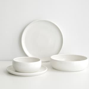 Peut inclure: Un ensemble de trois bols en céramique blanche, comprenant un petit bol avec une soucoupe, un bol de taille moyenne et un grand bol.