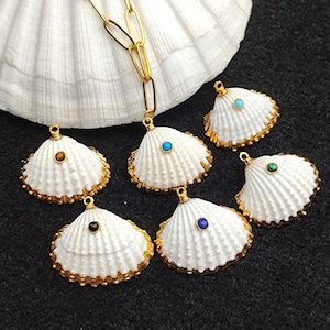 May include: Six white seashell charms with gold trim and a variety of colored gemstones in the center. The charms are hanging from a gold chain.