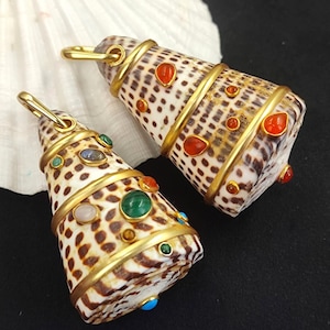 May include: Two cone-shaped pendants made from shells, adorned with gold-colored metal bands and various gemstones. The shells have a speckled pattern. One pendant features red, green, and blue gemstones. The other pendant has red gemstones.