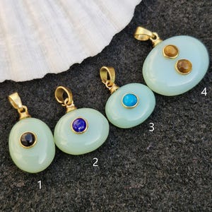 May include: Five oval-shaped pendants with gold accents and different colored gemstones. The pendants are numbered 1 through 5.