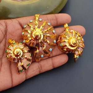Peut inclure: Trois pendentifs en forme de coquille plaqués or avec des accents de pierres précieuses colorées. Les coquilles sont en forme de spirale et présentent un design détaillé.