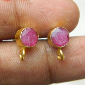 Pu&ograve; includere: Un paio di orecchini d'oro con accenti di pietre preziose rosa. Gli orecchini hanno un piccolo anello in basso.