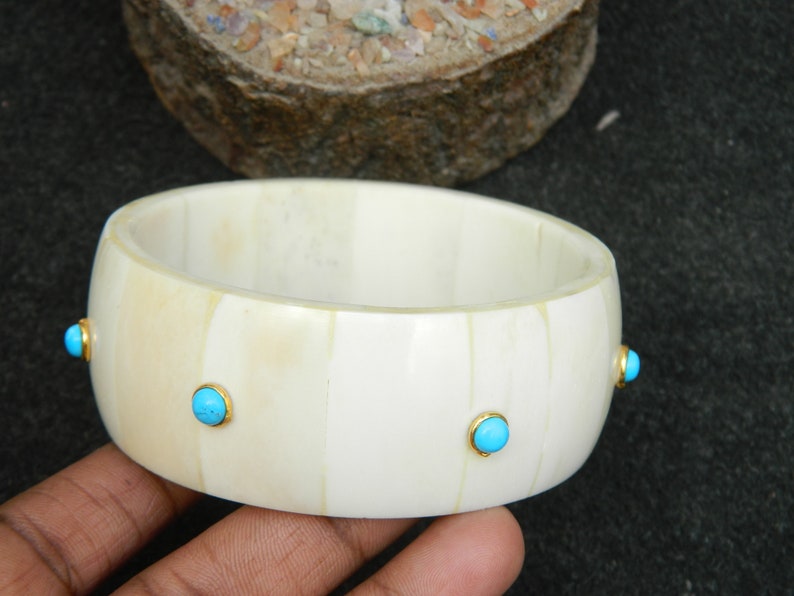 May include: White bone bangle bracelet with four turquoise blue stones set in gold.