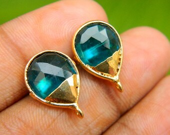 May include: Two teardrop-shaped turquoise blue glass beads with gold accents and a gold loop for hanging.