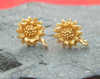 May include: A pair of gold-tone sunflower earrings with a detailed design. The earrings have a small loop on the back for attaching to an earring post.