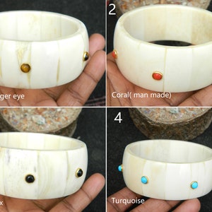 May include: Four bone bangles with different colored gemstones. The bangles are white with gold accents. The gemstones are tiger eye, coral, black onyx, and turquoise.