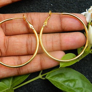May include: A pair of gold hoop earrings. The earrings are large and circular, with a simple design.