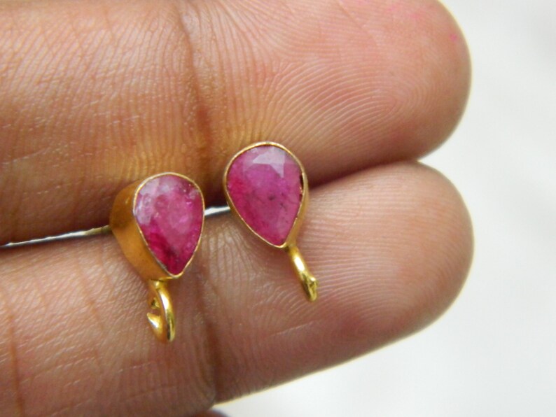 Pu&ograve; includere: Un paio di orecchini d'oro con pietre preziose rosa a forma di goccia.