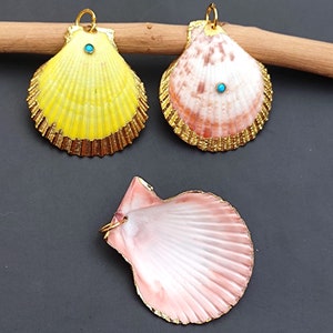 K&ouml;nnte beinhalten: Drei Muscheln mit goldenen Verzierungen und t&uuml;rkisfarbenen Akzenten. Die Muscheln sind in Gelb, Rosa und Wei&szlig; bemalt.
