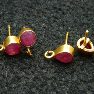 Pu&ograve; includere: Tre montature per orecchini in oro con accenti di pietre preziose rosse. Le montature hanno un anello a un'estremit&agrave; e un perno all'altra.