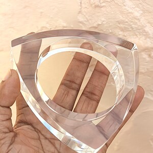 Op de afbeelding: Een heldere, vierkante acrylarmband met afgeronde binnenranden. De armband heeft een transparante uitstraling, waardoor licht erdoorheen kan schijnen. Het ontwerp is modern en minimalistisch, geschikt voor diverse stijlen.